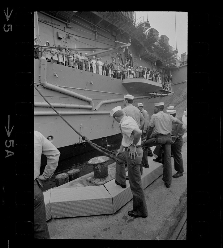 Sailors mooring USS Wasp and looking up at people on ship's deck