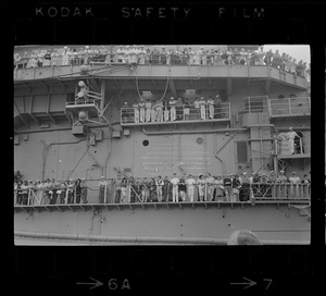 Sailors and passengers standing on ship's deck looking over railing