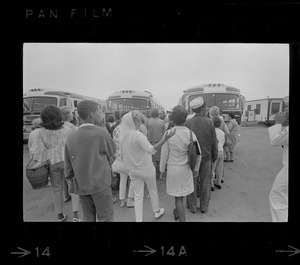 Group of civilians lining up to go onto buses