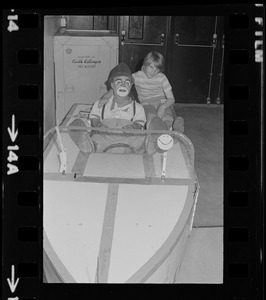 Clown sitting in a boat with child