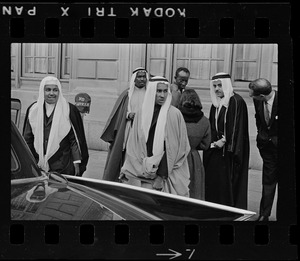 Group of men wearing bisht over thawb standing near a car outside Sheraton Plaza Hotel