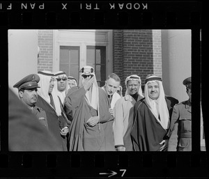 King Saud, center, leaving hospital and adjusting his glasses