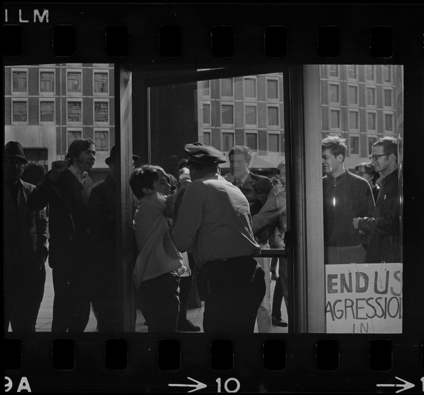 Police officer leading a protester out of a building