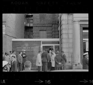 A group of people in conversation standing outside the entrance of the Boston Redevelopment Authority South End office