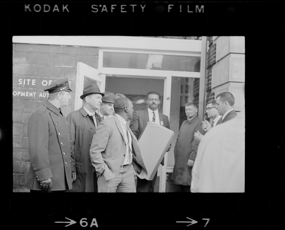 Man exiting Boston Redevelopment Authority office and holding a box