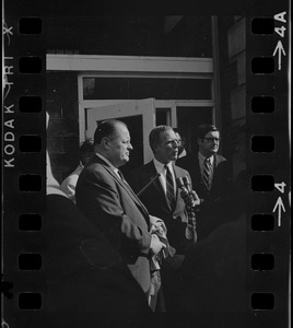 Hale Champion, left, looks on as Mayor White, right, speaks to a reporter during Boston Redevelopment Authority South End office sit-in