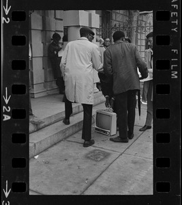 People outside Boston University administration building with a television