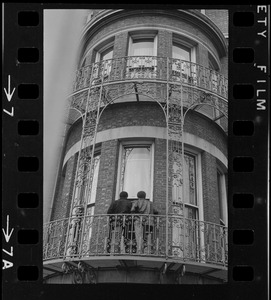 View of two people outside on ironwork balcony of Boston University administration building