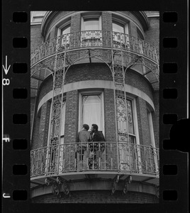 View of two people outside on ironwork balcony of Boston University administration building