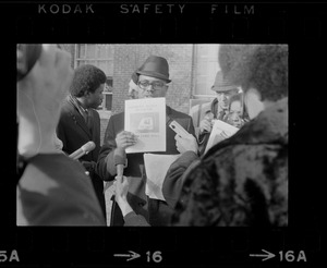 Young man holding a copy of "Brandeis Black Bulletin" while surrounded by press outside of Ford Hall during the Brandeis University sit-in