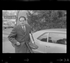 Morris B. Abram, president of Brandeis University, standing next to a car at Brandeis University