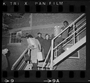 Students leave Ford Hall by the second-story rear fire escape while two men look on