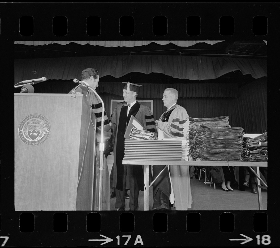 Brandeis University President Morris Abram giving an honorary degree to Norman Cousins, editor of the Saturday Review, at the Brandeis University commencement exercises