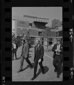 Boston University President Dr. Arland Christ-Janer walking with two others outside building at Students for a Democratic Society demonstration