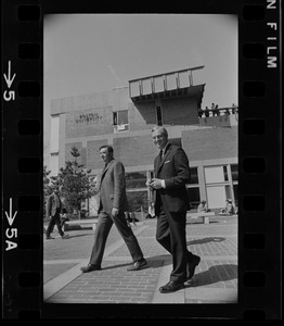 Boston University President Dr. Arland Christ-Janer walking with another man outside building at Students for a Democratic Society demonstration