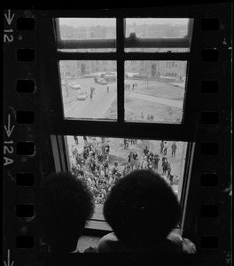 Two people looking at crowds through window during Boston College sit-in