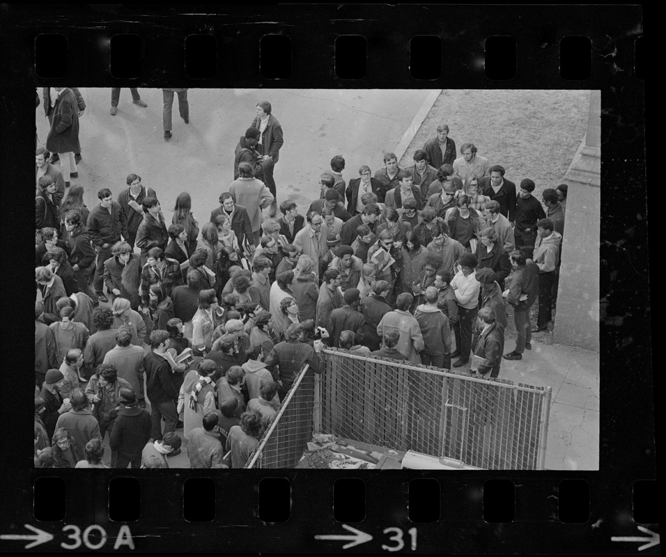 Crowd gathered around group of students seen in the middle talking during Boston College sit-in