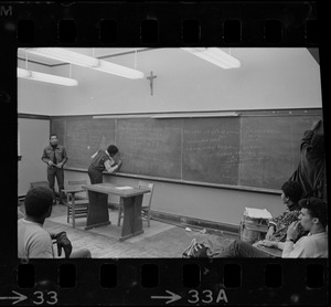 Students writing on chalkboard in a classroom during Boston College sit-in by 30 black students