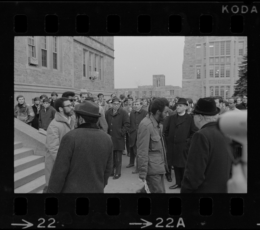 Crowd outside of Gasson Hall during Boston College sit-in while students exit building, one carrying a chain