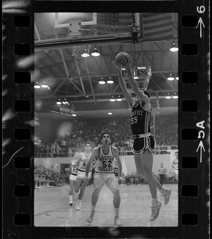 Providence College basketball player (no. 55) coming up for shot as Boston College player no. 50 stands by to defend