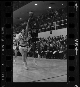 Boston College player (no. 50) tries to block Providence College player no. 25 as he makes a shot during a basketball game