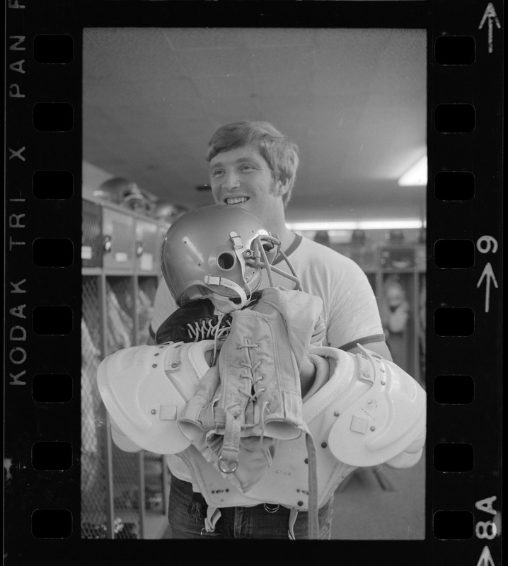 Boston College football player holding helmet, pads and gear