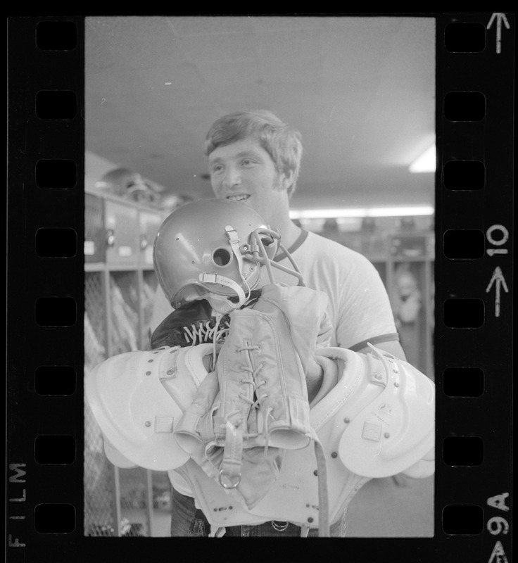 Boston College football player holding helmet, pads and gear