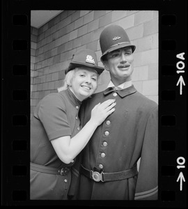 Female police officer poses with a male mannequin in police uniform