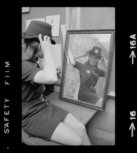 Female police officer adjusting Irish derby police cap in mirror