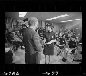 Mayor Kevin White and unidentified woman talk on stage in front of first female class of police officers