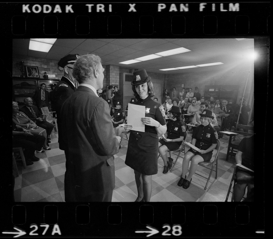 Mayor Kevin White and unidentified woman talk on stage in front of first female class of police officers