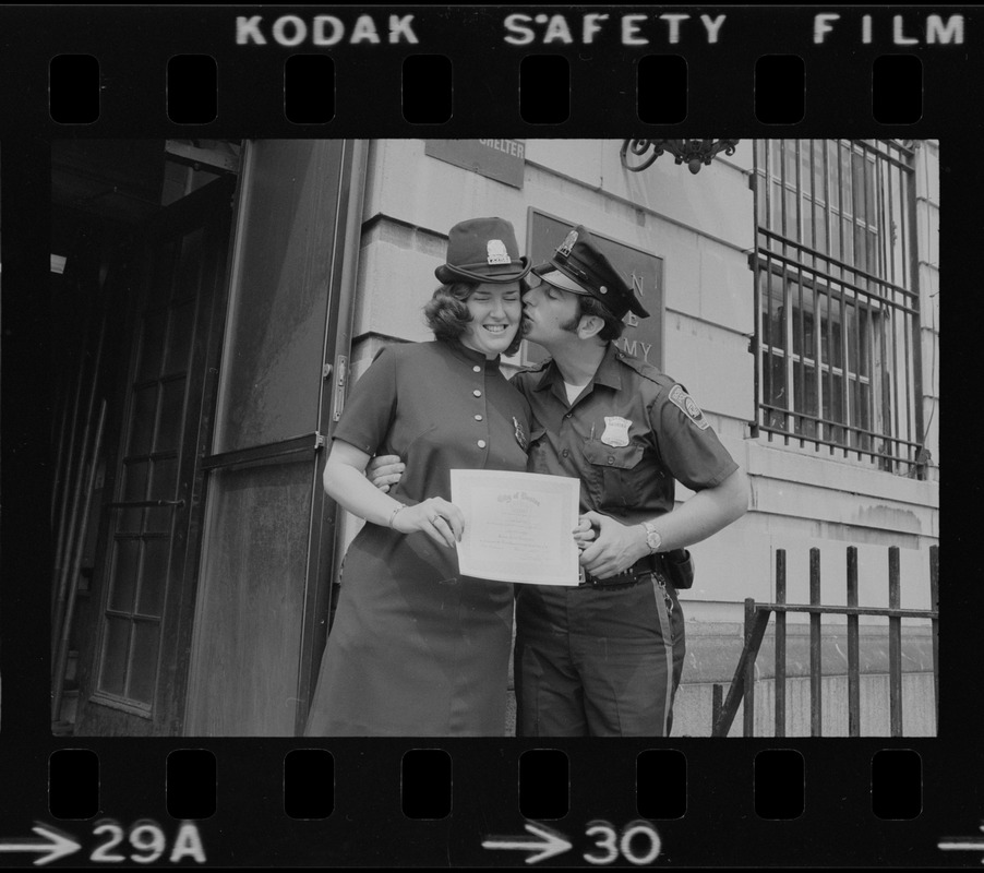 Diane Hofferty, a graduate of first female class of police officers, receives a kiss from a male officer