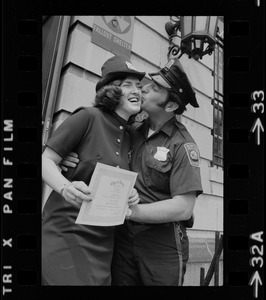 Diane Hofferty, a graduate of first female class of police officers, receives a kiss from a male officer