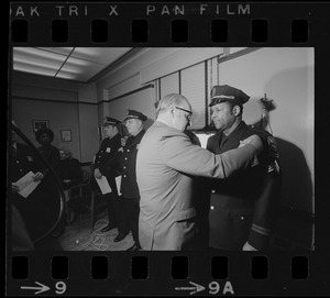 Police commissioner Edmund L. McNamara pins badge on with newly promoted lieutenant Leroy B. Chase