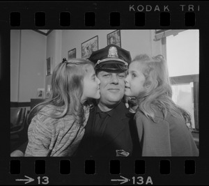 Happy about dad's promotion, Karyn, 8, and Cheryl, 6, use their father, Lieutenant Earl B. Crocker, as a target for kissing practice after ceremonies yesterday at Boston Police Headquarters