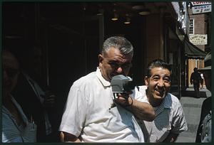 Two men on street, one holding a camera, Boston