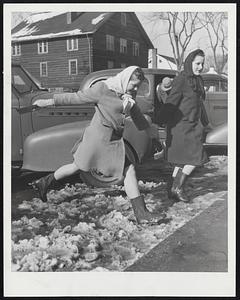Paging Sir Walter Raleigh -- In the absence of a cape-equipped gallant, Pauline Howard negotiates a Belmont slush puddle with a leap and the aid of Jackie Currier. Both are Belmont High students.