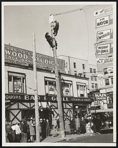 Striking Linemen Stage Sit-down Atop Poles. Flushing: N.Y.-Five Edison Company Linemen fastened their safety belts around two-fifty-foot poles on Main Street and Roosevelt avenue today, as a protest demonstration against the layoff of 350 employees and announced that they would not come down until the discharged workers were reinstated. Police reserves were called out to straighten out a traffic snarl but made no attempt to dislodge the pole-sitters. The three men shown on this pole are William J. Kennedy, former lineman and CIO organizer: Edward Harrison and Thomas Gillen.