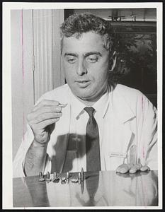 Dr. Raphael Adar examines a bent bullet he removed from an Arab POW. Lined up on the table are several other bullets and fragments he removed to help save the lives of wounded Arabs. Working beside him in the operating room were Arab doctors.