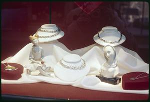Window display of necklaces and figurines of women