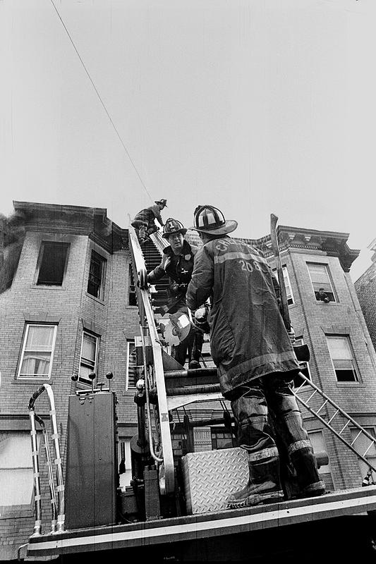 Firefighter Ed Buckley on L1s turntable as firefighter Joe McDonald descends with the power saw and firefighter Jimmy Grafton at the tip of the ladder