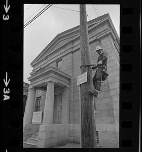 Man climbing pole near Customs House