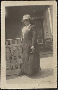 Woman wearing a hat stands in front of a fence
