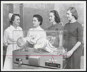 Useful Christmas Gift presented to the Cape Cod Hospital by the Hyannis Junior Woman's Club was this Isolette Rocker, used to aid premature babies. That's a doll in the one being presented to Mrs. Ida Crocker, assistant director of nursing at the hospital, by Mrs. Anthony Casella, Mrs. Charles Wisenor and Miss Joan Barrows, from left.