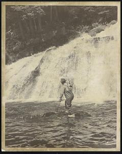 New Hampshire Fish and Game Photo -- Uel Gardner. The music of high falling water is in tune to a bowed rod and a tight line of this happy fisherman.