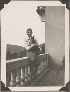 An unidentified woman sitting on a balustrade holding a Boston terrier
