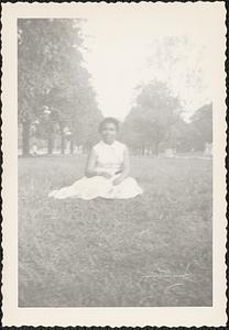 A young woman sits on grass