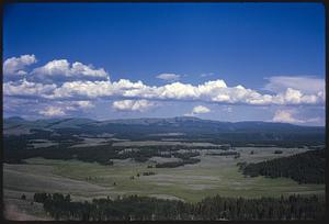 Landscape with plains, trees, hills, and mountains, likely Wyoming