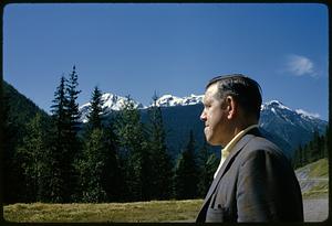 Profile view of man with trees and mountains in background, British Columbia
