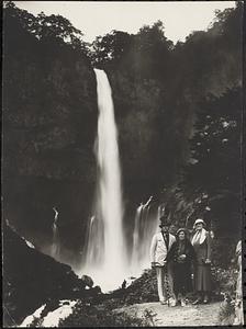 Three people standing in front of a waterfall